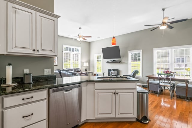 kitchen with dishwasher, sink, dark stone countertops, ceiling fan, and light hardwood / wood-style floors