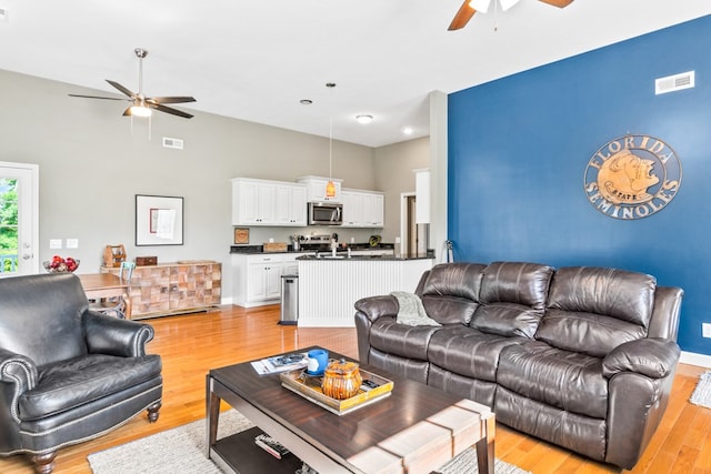 living room with ceiling fan and light wood-type flooring