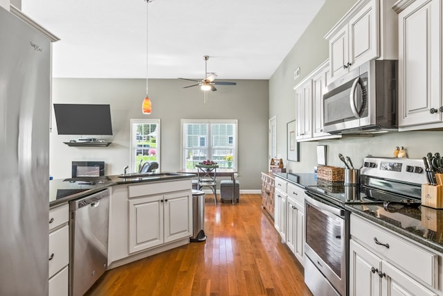 kitchen featuring dark hardwood / wood-style floors, pendant lighting, sink, white cabinets, and stainless steel appliances