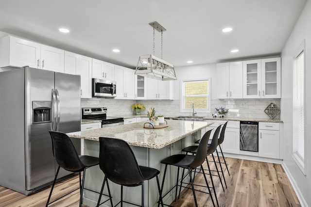 kitchen featuring appliances with stainless steel finishes, a sink, a breakfast bar, a center island, and white cabinets