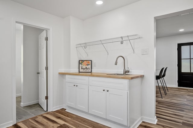 clothes washing area featuring a sink, wood finished floors, recessed lighting, and baseboards