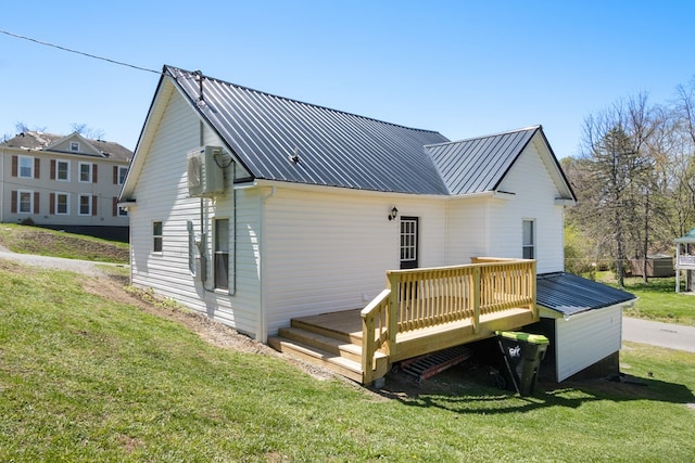 rear view of house featuring a deck, a yard, and metal roof