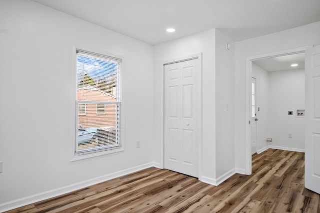 empty room featuring wood finished floors, baseboards, and recessed lighting