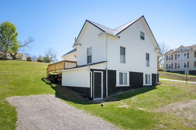 view of side of home featuring a lawn, a wooden deck, and metal roof