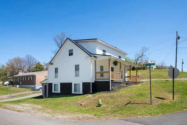 view of side of home featuring covered porch and a yard