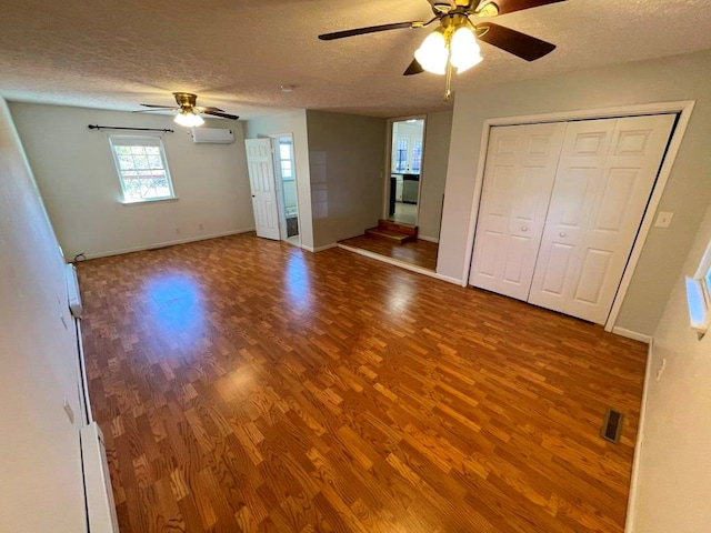 interior space featuring ceiling fan, hardwood / wood-style floors, a textured ceiling, and an AC wall unit