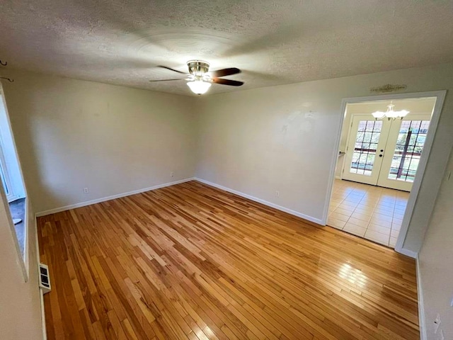 spare room featuring ceiling fan, a textured ceiling, light wood-type flooring, and french doors