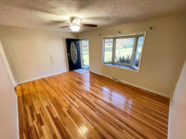 spare room with ceiling fan, light hardwood / wood-style flooring, and a textured ceiling