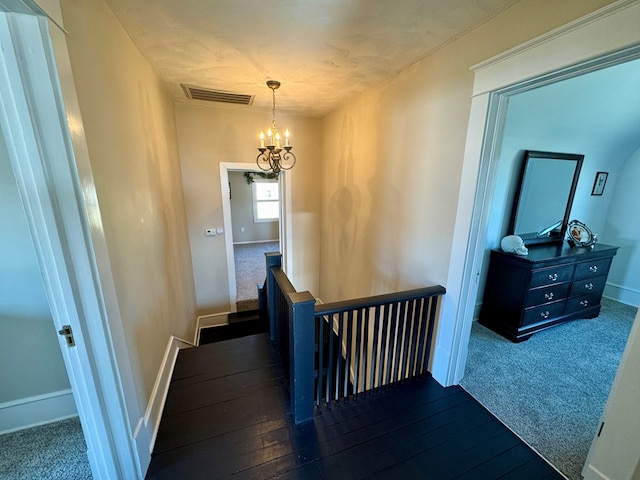 corridor with dark hardwood / wood-style floors and a notable chandelier