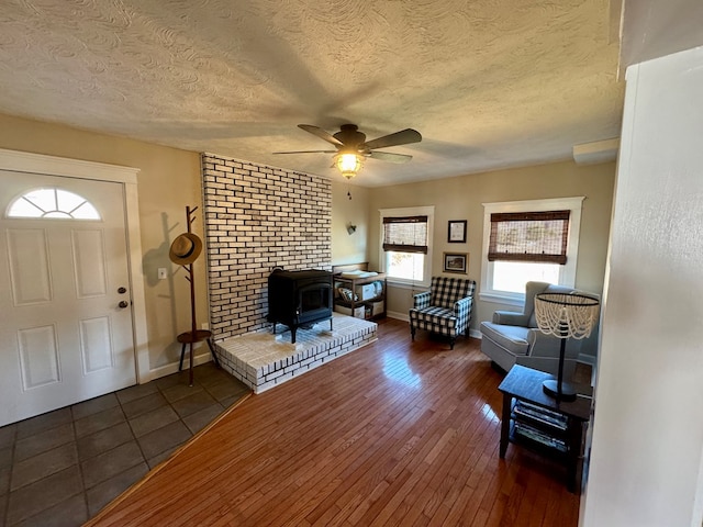 foyer entrance with a textured ceiling, dark hardwood / wood-style floors, ceiling fan, and a wood stove