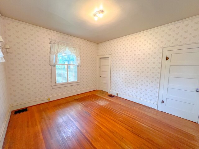 unfurnished bedroom with hardwood / wood-style floors, a closet, and ornamental molding