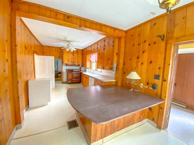 kitchen with a baseboard radiator, ceiling fan, white dishwasher, stove, and wooden walls