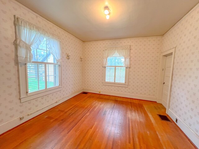 empty room featuring hardwood / wood-style flooring and ornamental molding