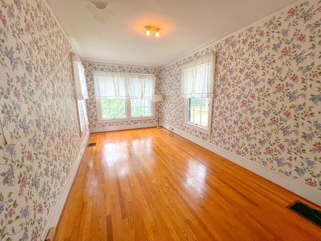 empty room with ornamental molding and hardwood / wood-style floors