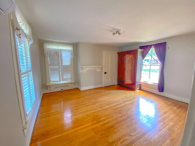 empty room featuring a wall mounted AC and light wood-type flooring