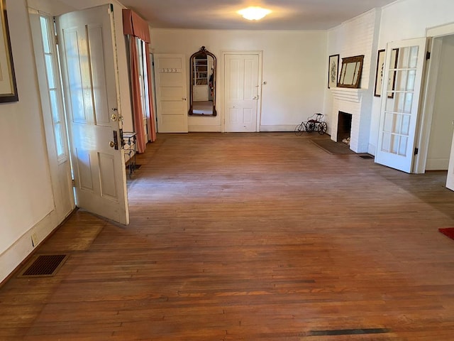 foyer entrance with a brick fireplace and dark hardwood / wood-style floors