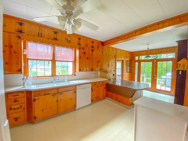 kitchen with dishwasher, hanging light fixtures, wooden walls, french doors, and kitchen peninsula