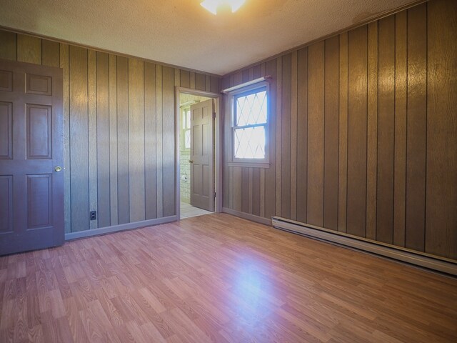 empty room featuring wood walls, wood finished floors, and a textured ceiling