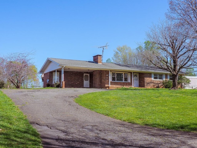 single story home featuring a chimney, driveway, a front yard, and brick siding