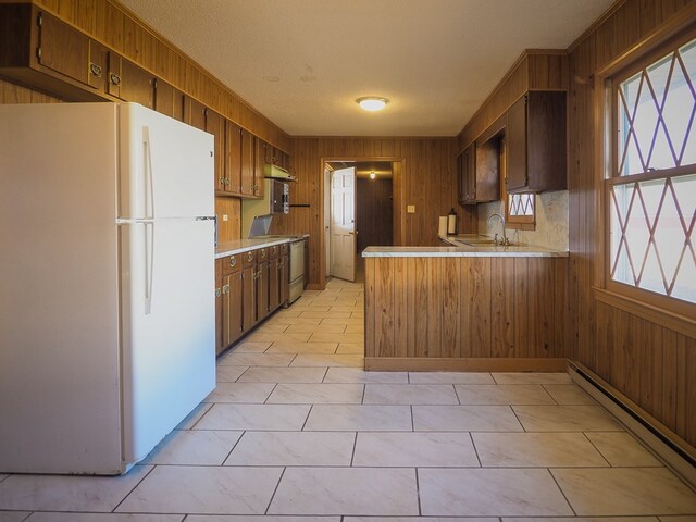 kitchen with a sink, light countertops, freestanding refrigerator, baseboard heating, and stove