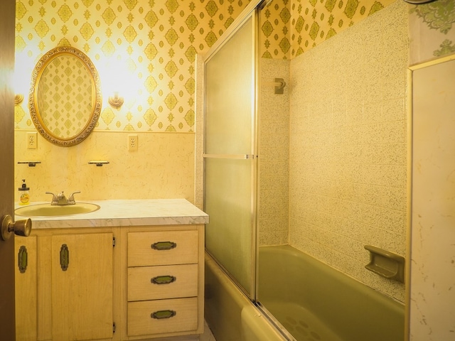full bathroom featuring vanity, shower / bath combination with glass door, and wallpapered walls