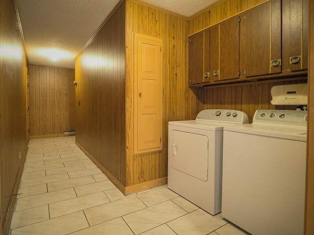 clothes washing area with light tile patterned floors, washing machine and dryer, a textured ceiling, and cabinet space