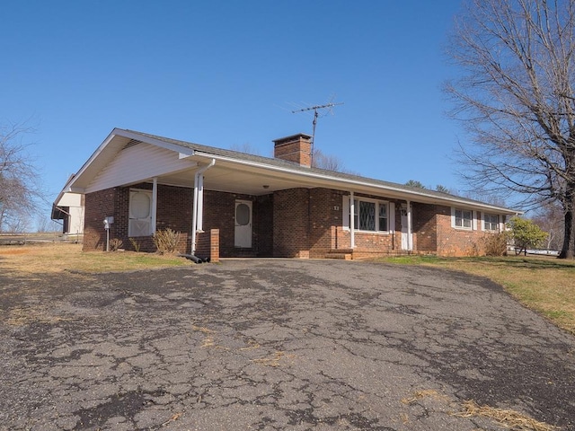 single story home with brick siding, a chimney, and aphalt driveway