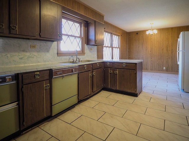 kitchen with dark brown cabinetry, an inviting chandelier, a peninsula, freestanding refrigerator, and dishwasher