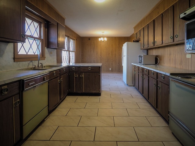kitchen featuring dishwashing machine, a chandelier, stainless steel microwave, wooden walls, and electric range oven