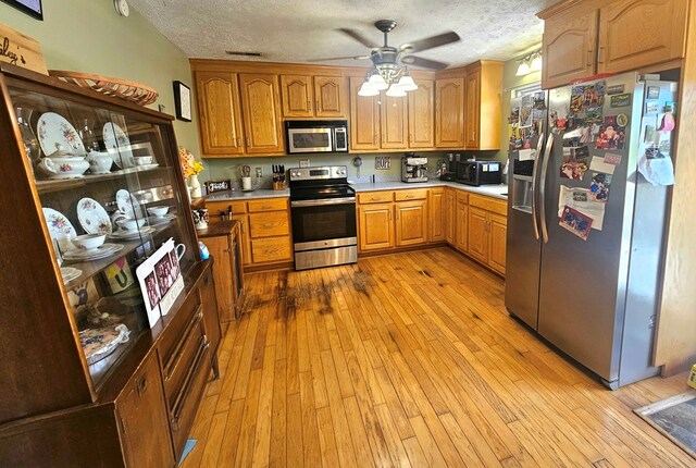 290 Hummingbird Hl, Tazewell, VA 24651 - kitchen with appliances with stainless steel finishes, a ceiling fan, a textured ceiling, light wood finished floors, and light countertops