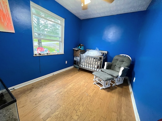 290 Hummingbird Hl, Tazewell, VA 24651 - bedroom featuring wood finished floors, a textured ceiling, baseboards, a ceiling fan, and a nursery area