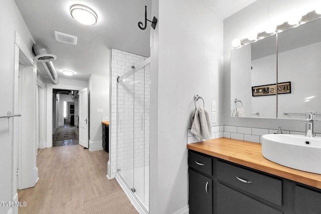 24 6th St, Bristol, TN 37620 - bathroom with decorative backsplash, vanity, wood finished floors, and a stall shower
