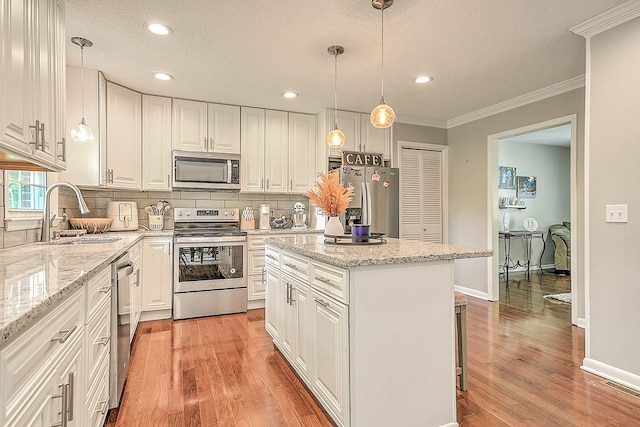 420 Brookwood Dr, Bristol, TN 37620 - kitchen featuring appliances with stainless steel finishes, crown molding, decorative backsplash, white cabinetry, and a kitchen island