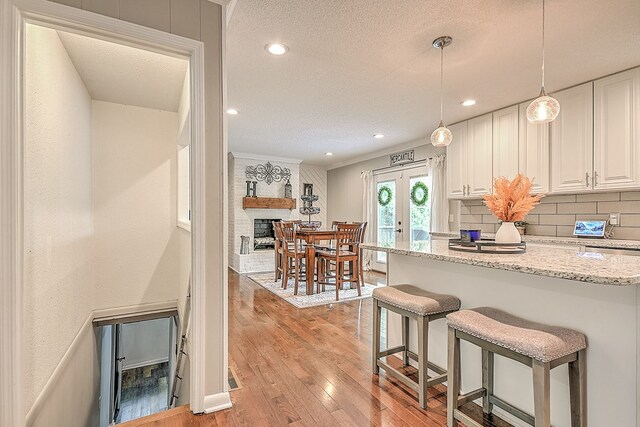 420 Brookwood Dr, Bristol, TN 37620 - kitchen featuring a textured ceiling, light wood finished floors, tasteful backsplash, white cabinets, and light stone counters