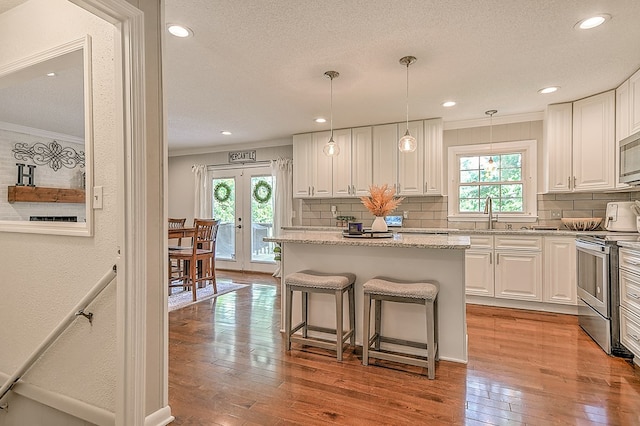 420 Brookwood Dr, Bristol, TN 37620 - kitchen featuring appliances with stainless steel finishes, crown molding, decorative backsplash, light wood-style floors, and white cabinetry