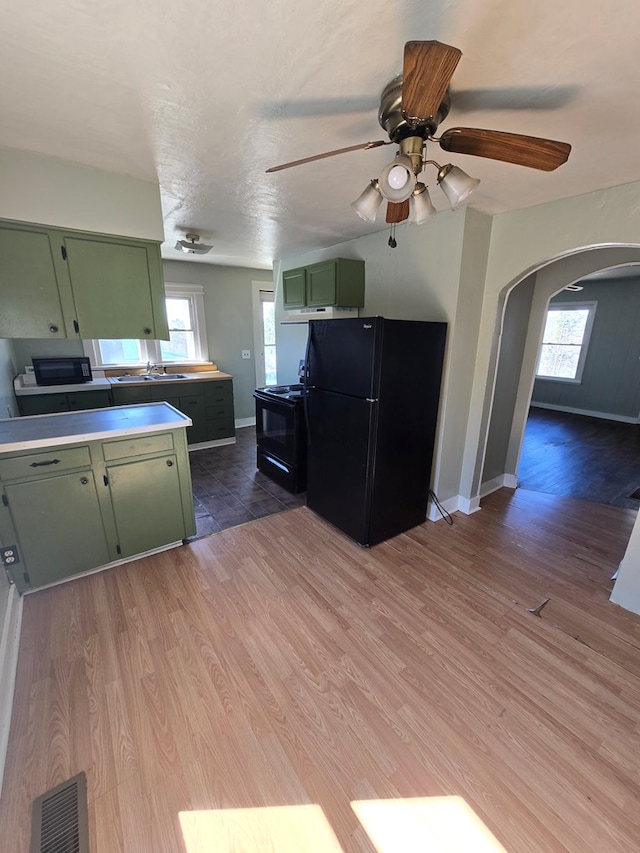 kitchen featuring black appliances, visible vents, light wood-style floors, and green cabinetry