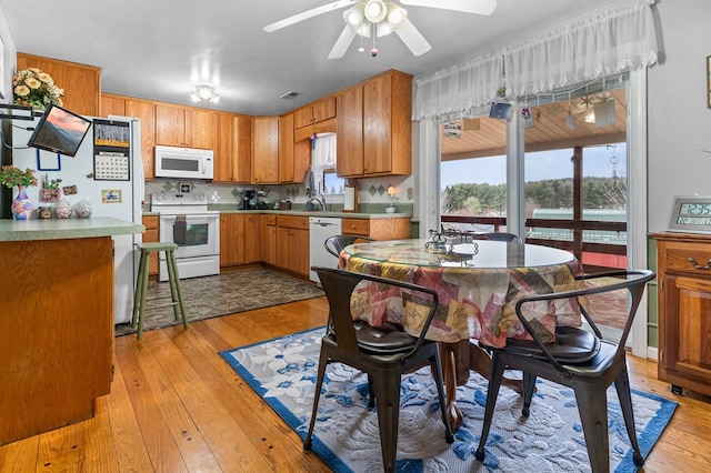 kitchen featuring sink, white appliances, ceiling fan, light hardwood / wood-style floors, and backsplash