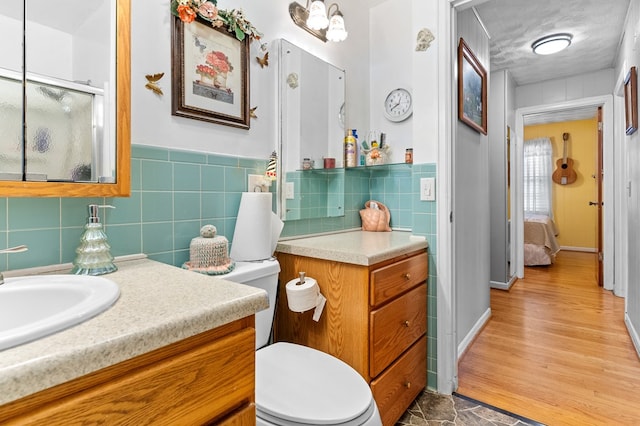 bathroom with hardwood / wood-style flooring, vanity, toilet, and tile walls