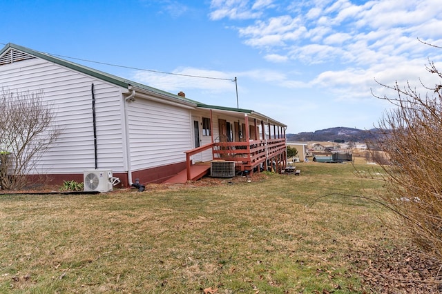 exterior space with ac unit, central AC, a mountain view, and a lawn