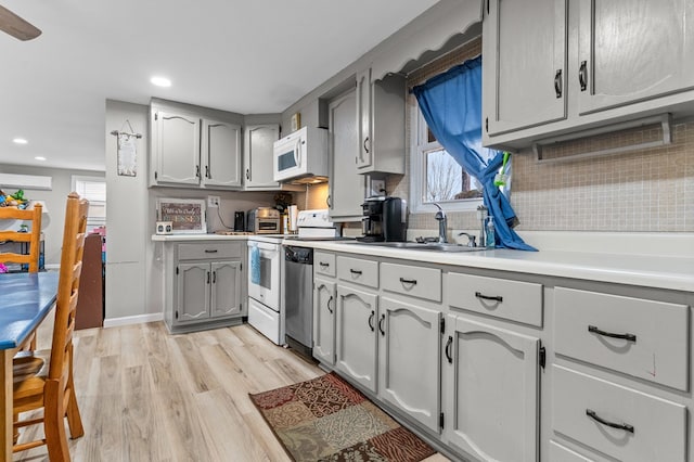 kitchen with white appliances, a healthy amount of sunlight, sink, and light wood-type flooring