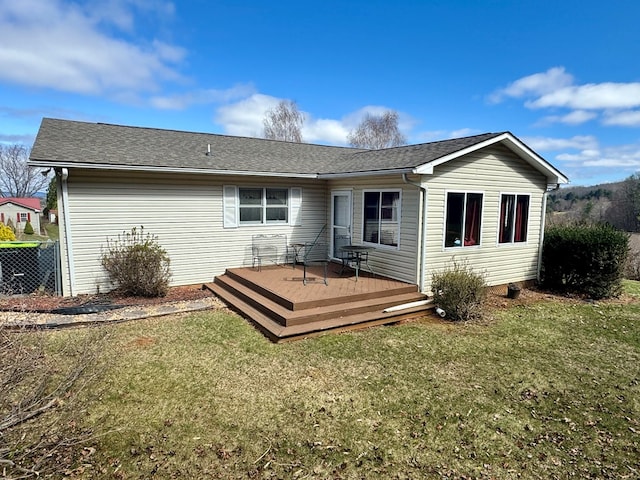 back of property featuring roof with shingles, a wooden deck, and a yard