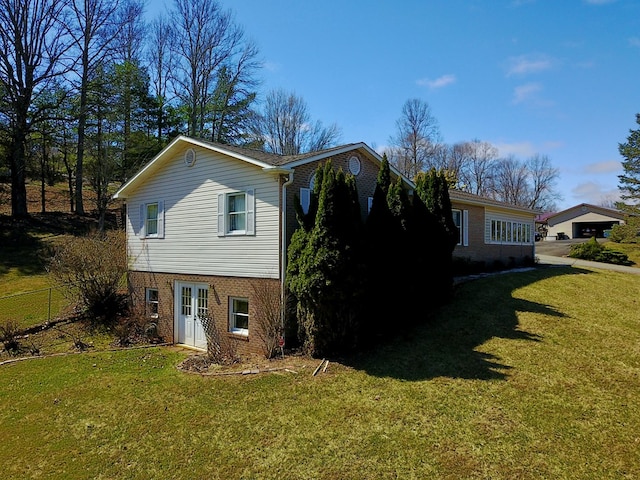 view of property exterior with a lawn, brick siding, and fence