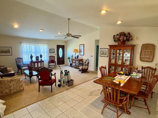 dining space with ceiling fan, light carpet, vaulted ceiling, and light tile patterned flooring