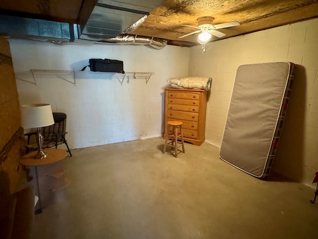 unfinished below grade area featuring concrete block wall and a ceiling fan