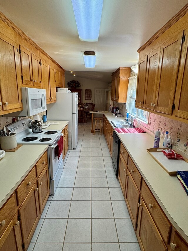 kitchen with white appliances, light countertops, brown cabinets, a sink, and light tile patterned floors