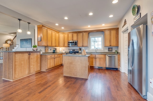 kitchen featuring a kitchen island, recessed lighting, hanging light fixtures, dark wood-type flooring, and appliances with stainless steel finishes