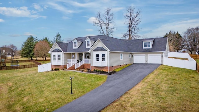 view of front of home featuring a front lawn, fence, a garage, and aphalt driveway