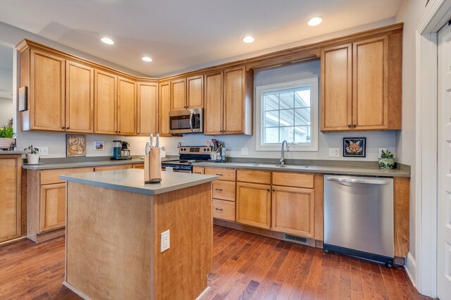 kitchen featuring a center island, dark wood-type flooring, recessed lighting, stainless steel appliances, and a sink