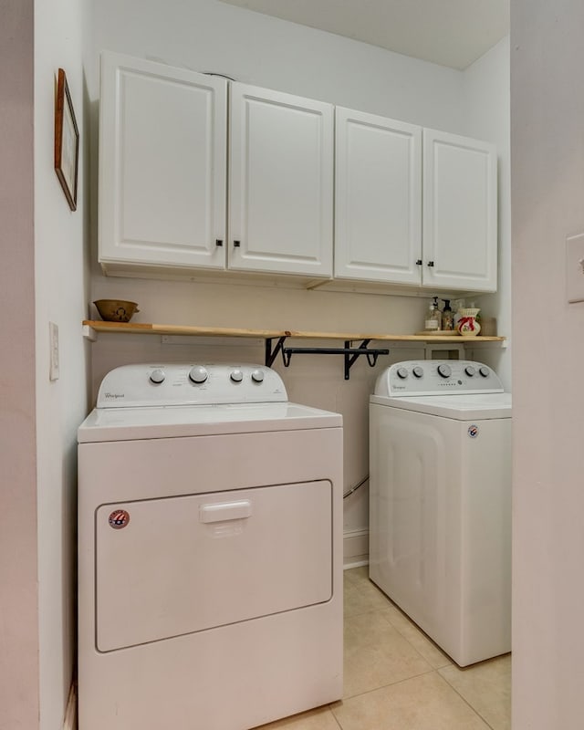 laundry room with separate washer and dryer, light tile patterned floors, and cabinet space