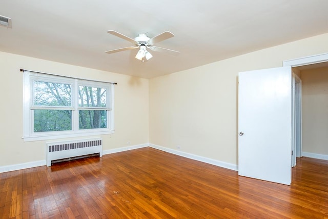 empty room featuring baseboards, radiator heating unit, hardwood / wood-style flooring, and ceiling fan
